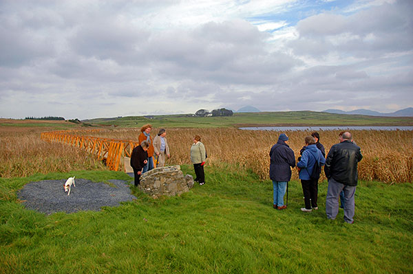 Picture of a group of visitors next to a information board, a new wooden walkway in the background