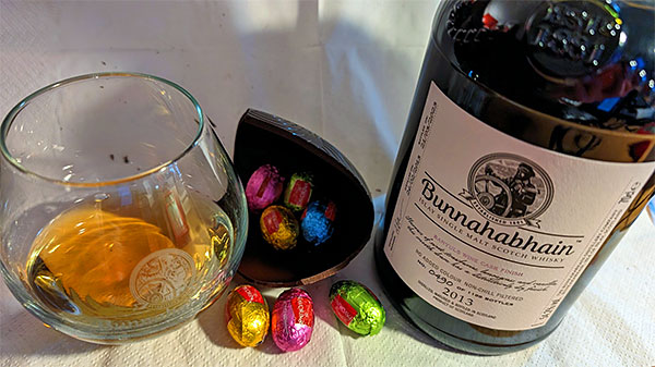 Picture of a bottle of Bunnahabhain Islay single malt whisky with a glass of it, also some chocolate Easter eggs